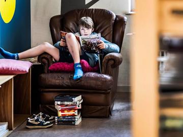 Willem (9) leest in de bruine zetel van Bib Joske