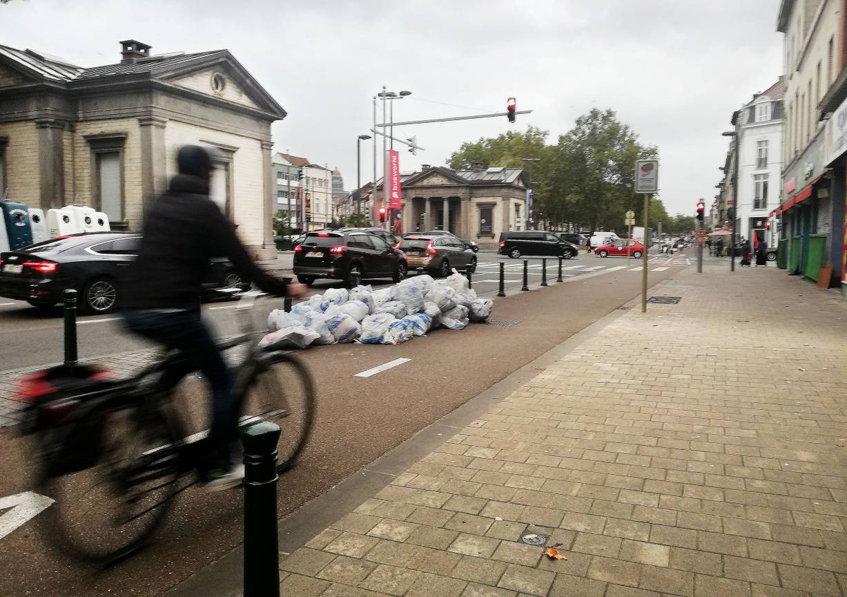 Huisvuilophaling op dinsdagochtend langs de kleine ring aan de Poincarélaan: vuilniszakken op en langs het fietspad