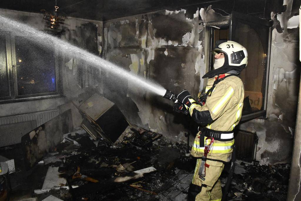 Iemand van de brandweer blust in een uitgebrande kamer van een gebouw in de Ankerstraat in Neder-Over-Heembeek
