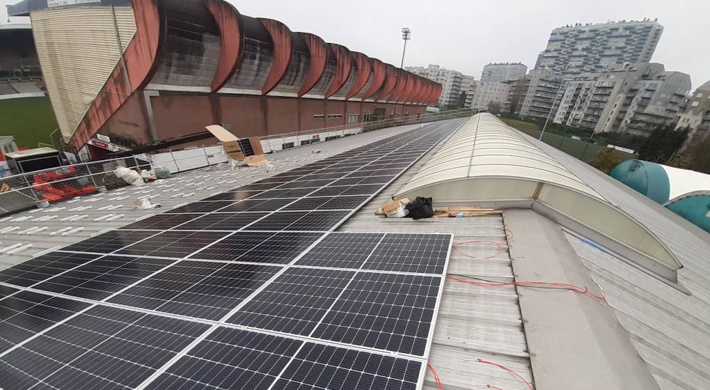 Zonnepanelen op het dak van de hal van Tennis Club Le Chalet, links in beeld het Edmond Machtensstadion