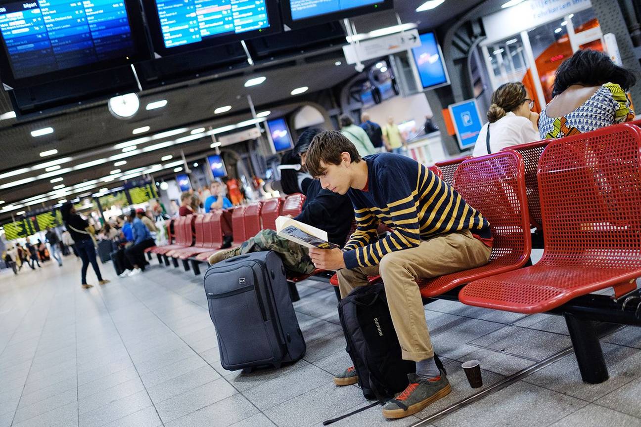 Lezend wachten op een trein in de centrale hal van het station Brussel-Zuid.