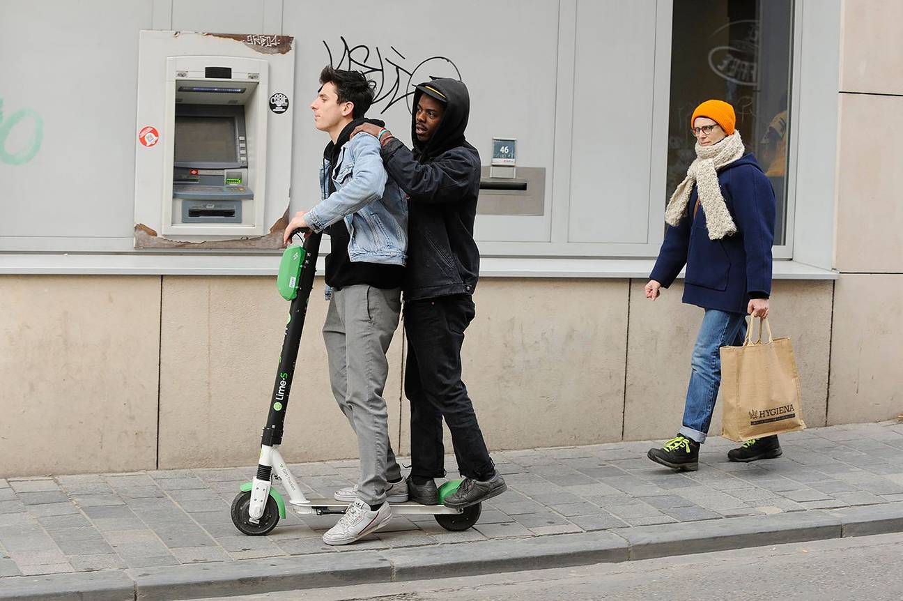 Elektrische deelsteps van Lime rijden langsheen een bancontactapparaat