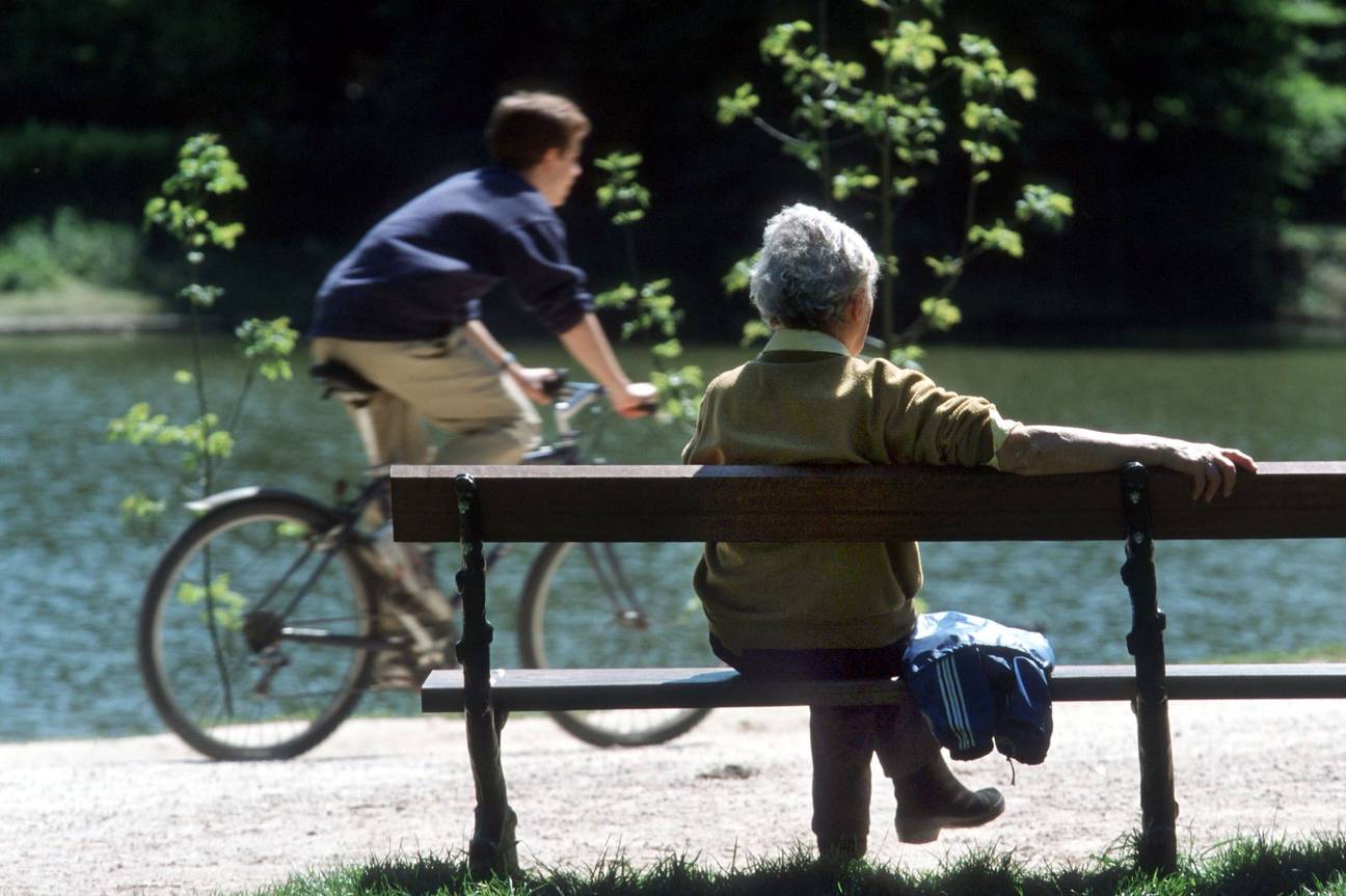 Bejaarde vrouw buiten op een rustbank in een park