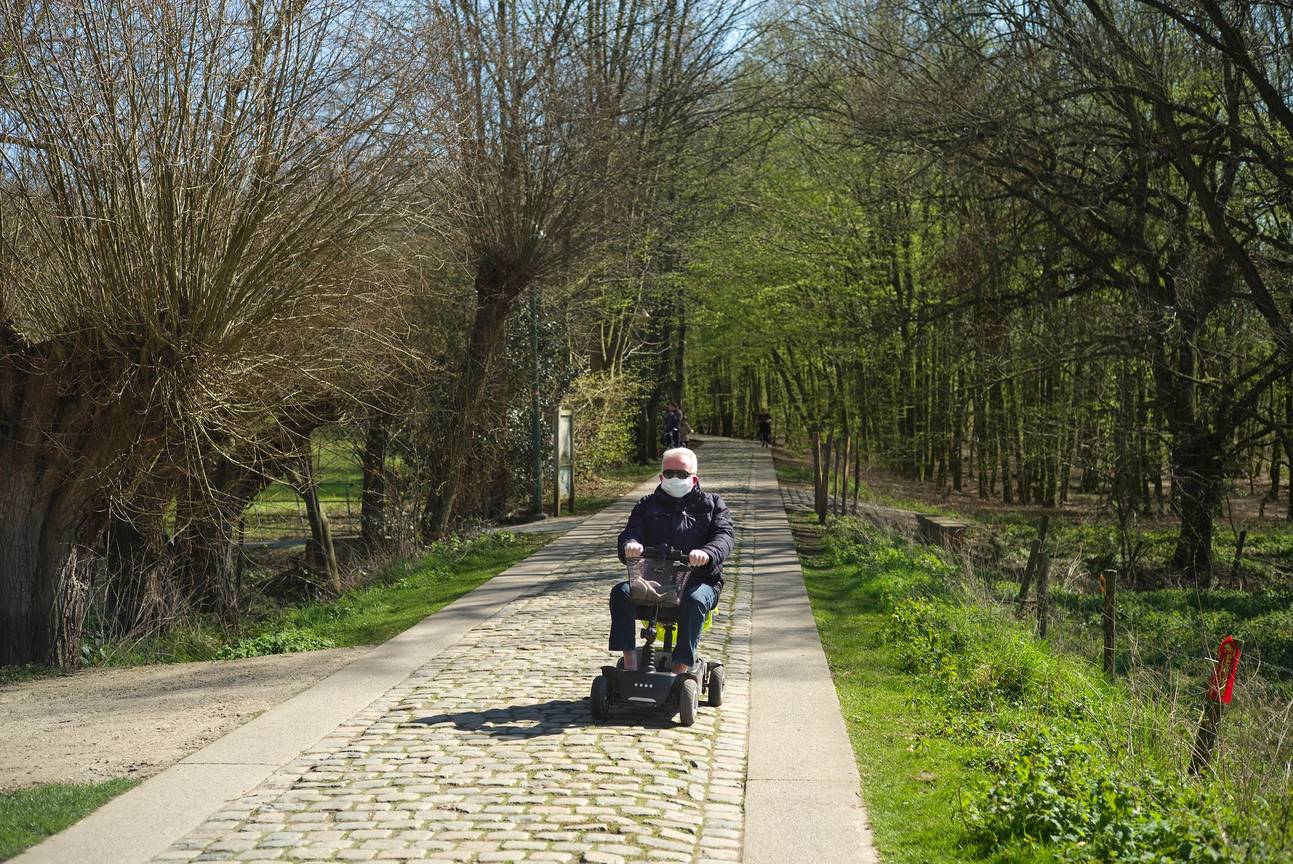 Een man maakt een tochtje met met mondmasker door Laarbeekbos op zijn scootmobiel tijdens de lockdown door het coronavirus (covid-19)