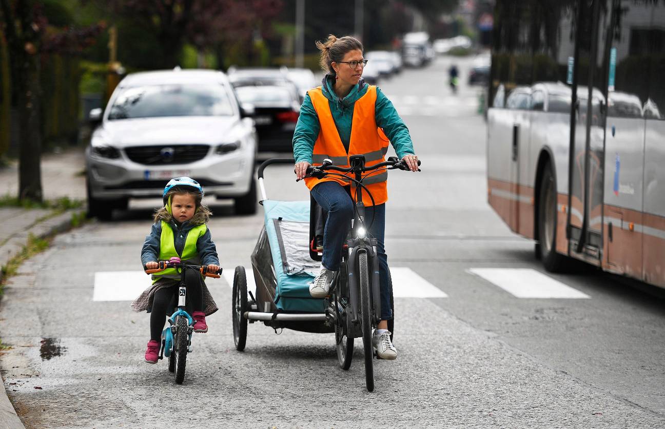 Mama met kinderen in fietskar en op kinderfiets. Door de regeringsmaatregelen om het coronavirus in te dijken is er weinig verkeer 