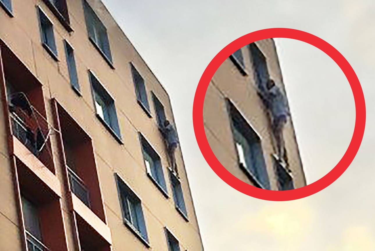 20200924 Bewoner wacht hangend aan vensterbank appartement op de brandweer uitgelicht