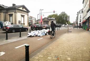 Huisvuilophaling op dinsdagochtend langs de kleine ring aan de Poincarélaan: vuilniszakken op en langs het fietspad