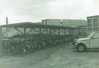 Fietsenstalling aan studentenwoningen, auto's, campus Oefenplein, 1973