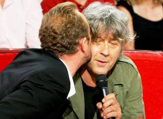 Arno krijgt een kus van acteur/regisseur Benoît Poelvoorde tijdens een uitzending van 'Vivement Dimanche' in 2005
