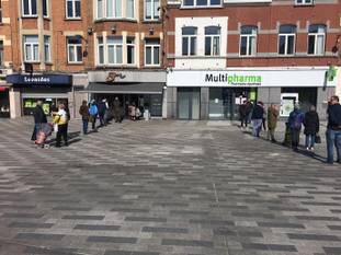 Het Spiegelplein in Jette rond de middag: een wachtrij voor de bakker, en een voor de apotheker