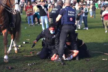 Politieagenten houden een jongere in bedwang tijdens onlusten in Ter Kamerenbos op 1 april 2021