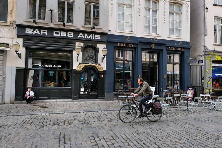 Een fietser rijdt langs de Bars des Amis en het Frites Atelier van Sergio Herman in de Sint-Katelijnestraat