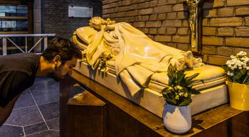 Jeroen Reyniers van het Koninklijk Instituut voor het Kunstpatrimonium (KIK) bij het beeld van de Heilige Theresa Van Lisieux in de Basiliek van Koekelberg. In de medaillon een stukje stof van een kleed van de Heilige Theresa.