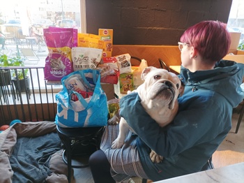 Dasha (haar gezicht is verborgen) poseert met een hond en met dierenvoeding