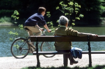 Bejaarde vrouw buiten op een rustbank in een park