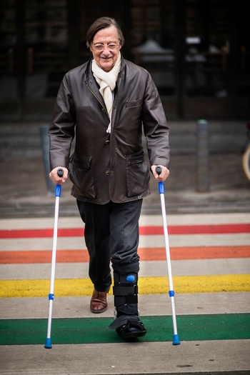 Alain Flausch, oug-topman MIVB op krukken holebi zebrapad Flageyplein