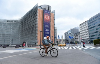 Een fietser aan het Berlaymontgebouw in de Europese wijk. Er is bijna geen verkeer door de lockdownmaatregelen van de overheid om covid-19, de ziekte veroorzaakt door het coronavirus, in te dijken