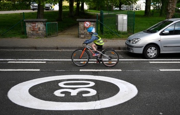 Een fietsend kind met fluohesje en  fietshelm in een Brusselse Zone 30