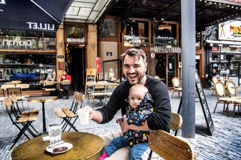 Olivier (45) zit met zijn eenjarige dochtertje op schoot op het uitgebreide terras van café Metteko