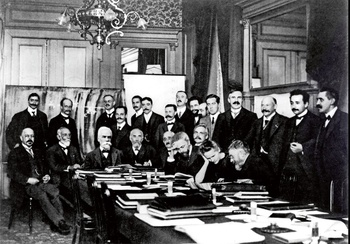 De eerste Solvayconferentie in Brussel, met Marie Curie aan tafel en Albert Einstein als tweede van rechts. Ernest Solvay is de derde van links, zittend, maar hij was niet aanwezig toen de foto werd genomen. Zijn portret werd er later ingeplakt.