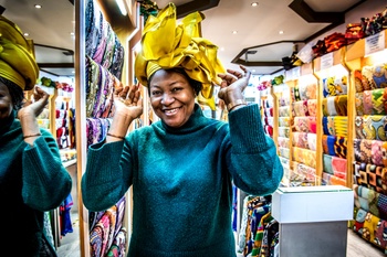 Clarisse Kapinga Kabasele past een gele hoed van glimmende wax in een stoffenwinkel in de Matongewijk