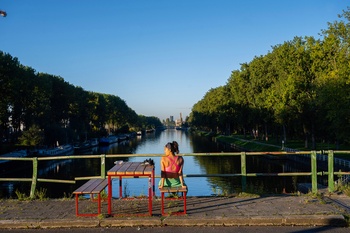 Hittegolf in Brussel, september 2023: Flow, openluchtzwembad aan het kanaal in Anderlecht. Een vrouw geniet van de zon op de Marchantbrug