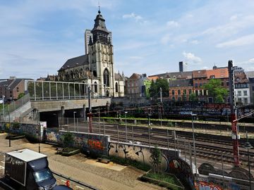 De sporen aan het treinstation Kapellekerk, gezien vanaf de Ursulinenstraat, met de Kapellekerk en het skatepark ervoor
