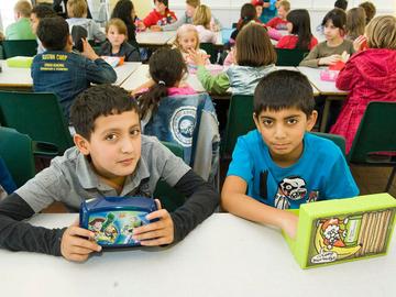 Leerlingen eten hun van thuis meegebrachte boterhammen in de refter van hun school