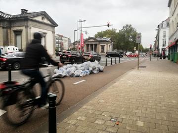 Huisvuilophaling op dinsdagochtend langs de kleine ring aan de Poincarélaan: vuilniszakken op en langs het fietspad
