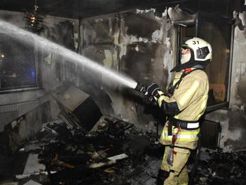 Iemand van de brandweer blust in een uitgebrande kamer van een gebouw in de Ankerstraat in Neder-Over-Heembeek