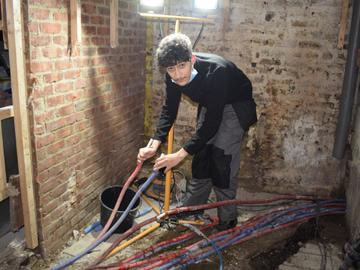 Een leerling van de Victor Hortaschool in Evere werkt aan waterleidingen in een gebouw