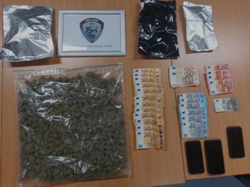 De buit van een drugsvangst uitgestald op een tafel: cannabis, biljetten en telefoons