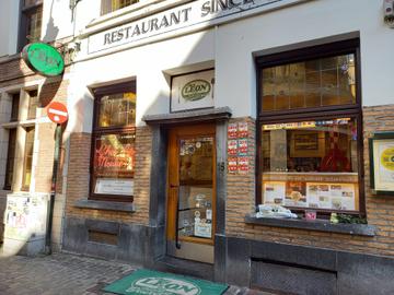 Een foto van de voorgevel van restaurant Chez Léon, met aan het raam enkele bloemen die daar neergelegd zijn na het overlijden van eigenaar Rudy Van Lancker