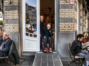 Geert Palmers en David Seffer in Café Winok in Schaarbeek, voorzien van een draagbare oprijplaat van Kinumai, de vzw die ze beiden oprichtten in 2020