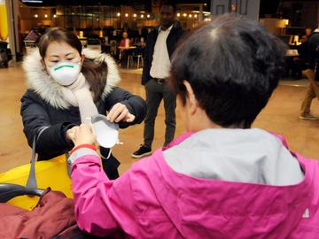 Een vlucht uit Beijing, net geland op Brussels Airport: personeel, douane en passagiers dragen mondmaskers als bescherming tegen het coronavirus