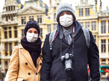 Toeristen op de Grote Markt beschermen zichzelf tegen het Coronavirus met een mondmasker