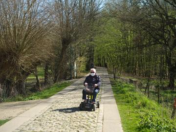 Een man maakt een tochtje met met mondmasker door Laarbeekbos op zijn scootmobiel tijdens de lockdown door het coronavirus (covid-19)