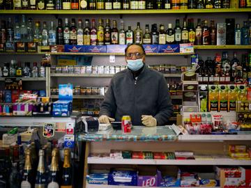 Nachtwinkel in Brussel tijdens de coronacrisis: de uitbater draagt een mondmasker om zichzelf (en eventueel anderen) te beschermen tegen het coronavirus en de ziekte corona-19