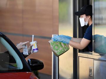 McDonald's drive-in fastfoodrestaurant: bediening met mondmasker om her risico op besmetting met het coronavirus te verminderen