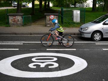 Een fietsend kind met fluohesje en  fietshelm in een Brusselse Zone 30