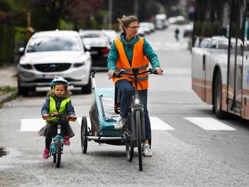 Mama met kinderen in fietskar en op kinderfiets. Door de regeringsmaatregelen om het coronavirus in te dijken is er weinig verkeer 