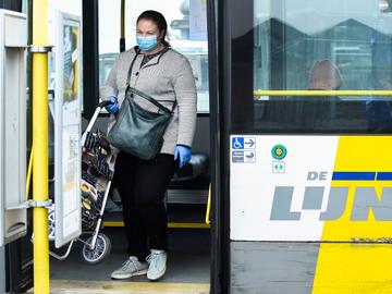 Een passagier met boodschappentas op een bus van De Lijn