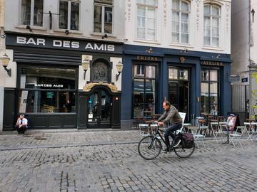 Een fietser rijdt langs de Bars des Amis en het Frites Atelier van Sergio Herman in de Sint-Katelijnestraat