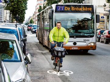 Een fietser deelt het verkeer met auto's en een MIVB)bus van Lijn 71 richting De Brouckère