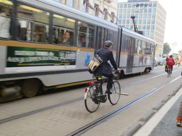 Een man fietst langs een tram van de MIVB in Brussel