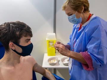 Een jonge man krijgt een coronavaccin toegediend in het vaccinatiecentrum aan de Heizel