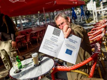 Een man op een Brussels terras toont zijn Covid Safe Ticket (CST) 