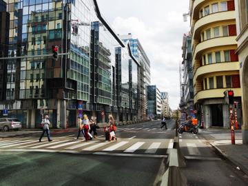 Het zebrapad oversteken in de Belliardstraat. Nieuwbouw, gerenoveerde kantoorgebouwen en enkele oudere gebouwen die de kaalslag van de voorbije decennia overleefden