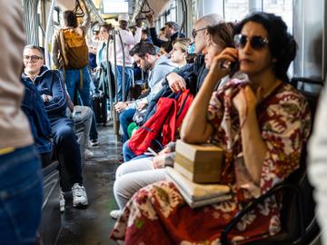 Een dame belt met haar smartphone op een tram van de MIVB