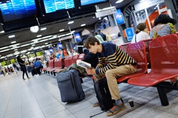 Lezend wachten op een trein in de centrale hal van het station Brussel-Zuid.